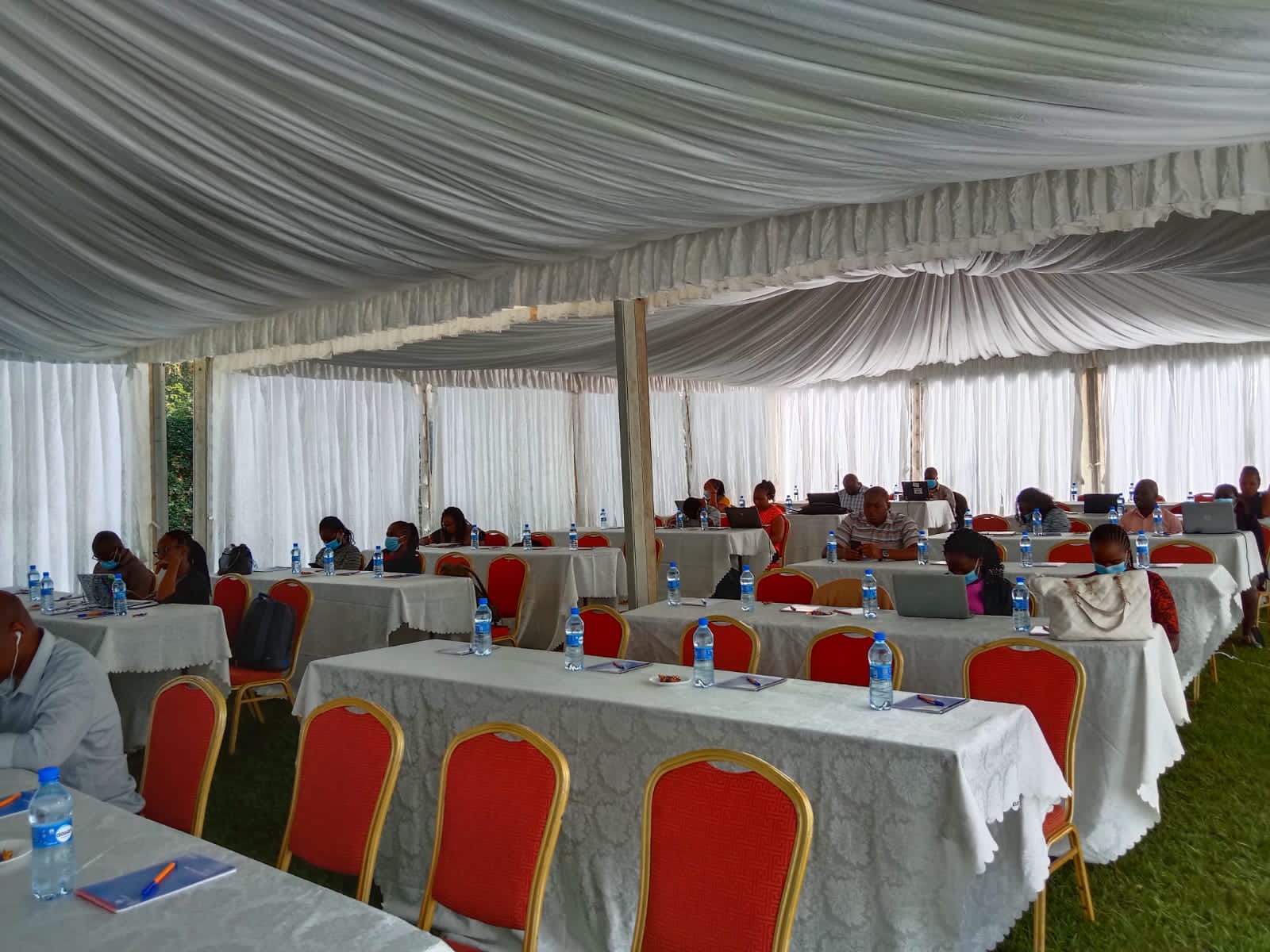 Elegant tent interior with draped fabric, white tablecloths, and formal place settings