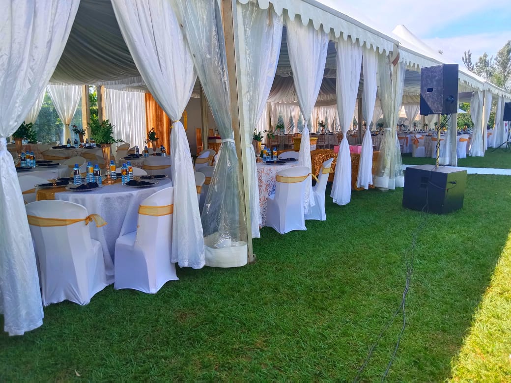Close-up of a white tent interior, with tables and chairs prepared for a formal event